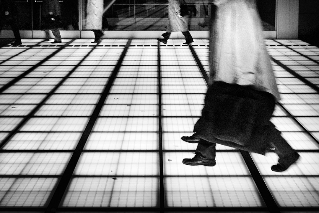 A person walking across a grid of light on the floor.